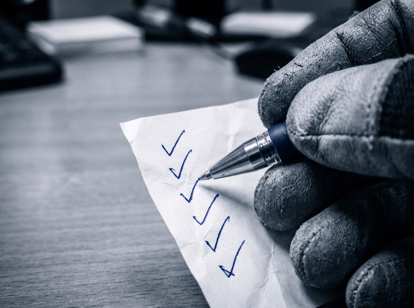 A hand ticking boxes on a printed checklist with a blue pen